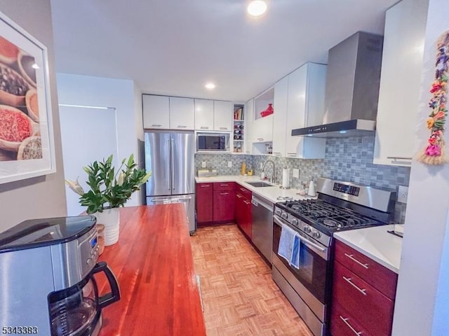 kitchen with a sink, tasteful backsplash, appliances with stainless steel finishes, wall chimney exhaust hood, and light countertops