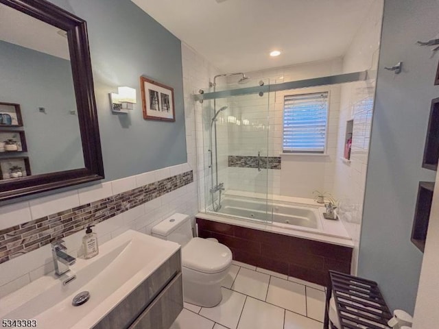 full bath featuring tile walls, toilet, tile patterned floors, vanity, and tiled shower / bath