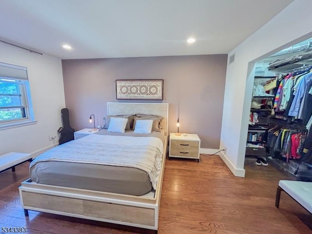 bedroom featuring wood finished floors, visible vents, baseboards, recessed lighting, and a spacious closet