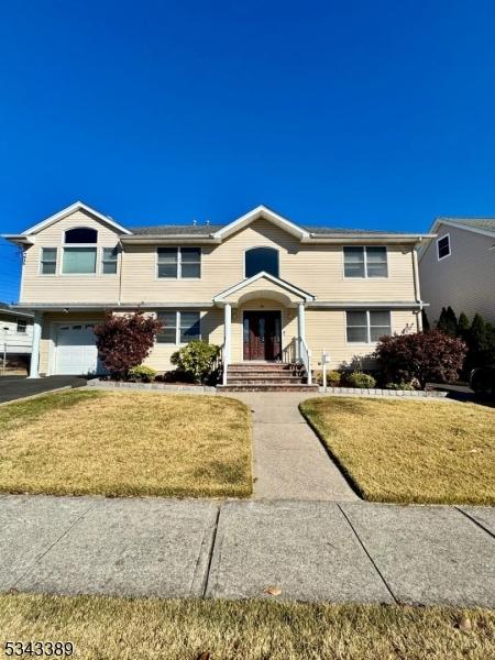 view of front of property featuring an attached garage, driveway, and a front lawn