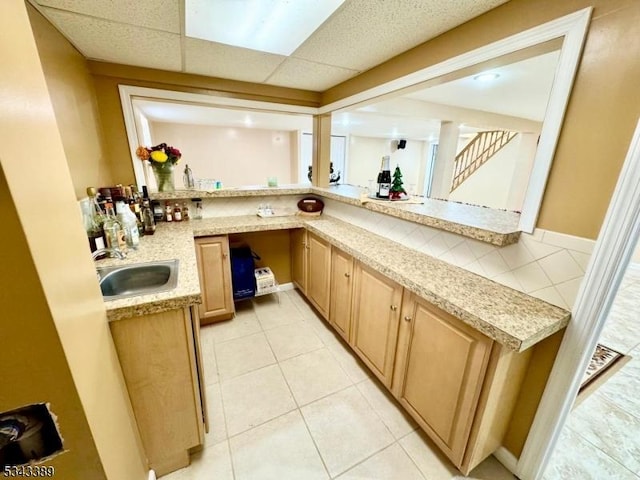 bar featuring light tile patterned flooring, a drop ceiling, indoor wet bar, and a sink