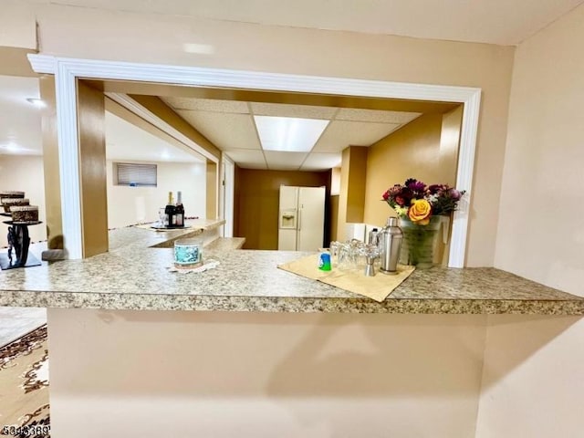 kitchen with a paneled ceiling and white refrigerator with ice dispenser