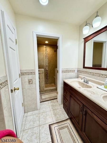 full bath featuring a sink, tile walls, a stall shower, and tile patterned flooring