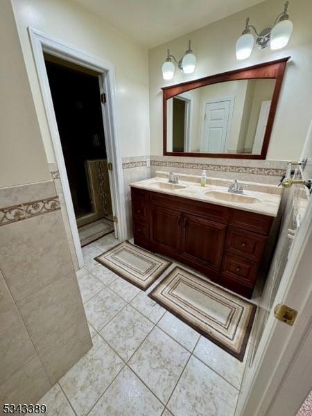 full bathroom with tile patterned flooring, tile walls, double vanity, and a sink