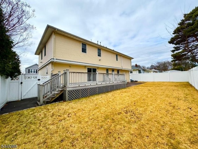 back of property with a yard, a deck, a fenced backyard, and a gate