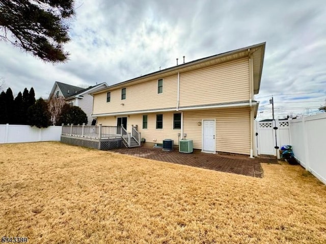 rear view of house featuring a deck, a lawn, central AC unit, and a fenced backyard