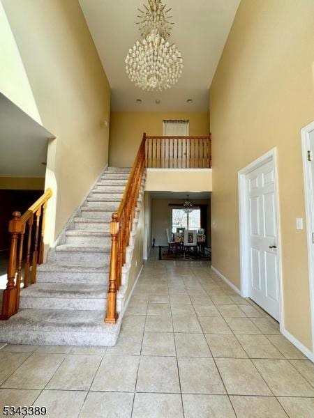 stairs featuring tile patterned flooring, baseboards, a high ceiling, and an inviting chandelier