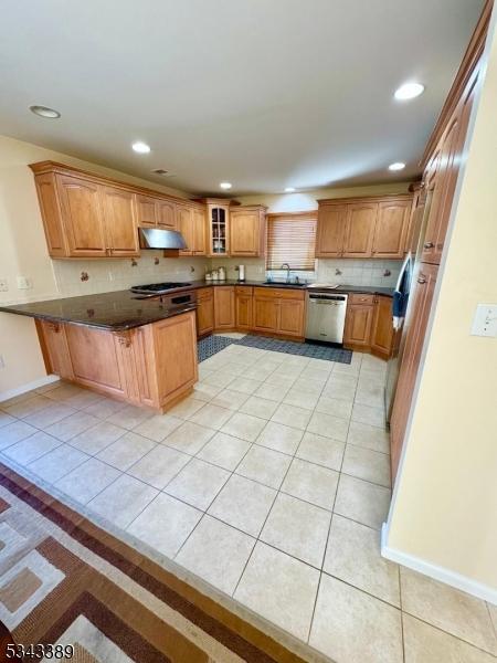 kitchen with under cabinet range hood, light tile patterned floors, a peninsula, and dishwasher