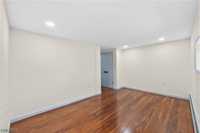 empty room with recessed lighting, a baseboard heating unit, baseboards, and wood finished floors