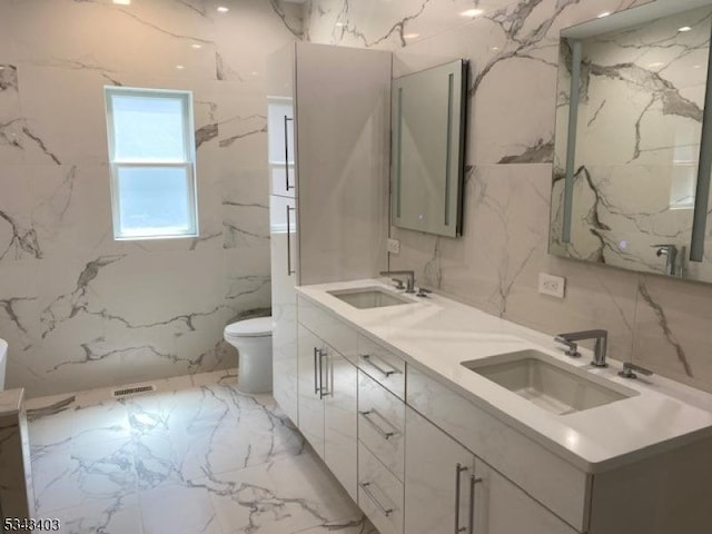 full bath featuring a sink, visible vents, toilet, and stone wall