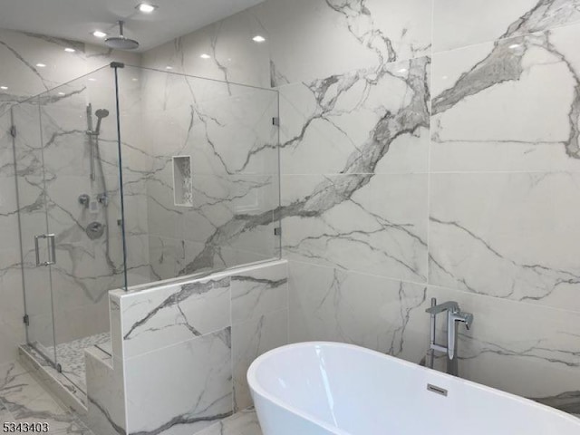 full bath featuring a freestanding tub, a marble finish shower, stone wall, and recessed lighting