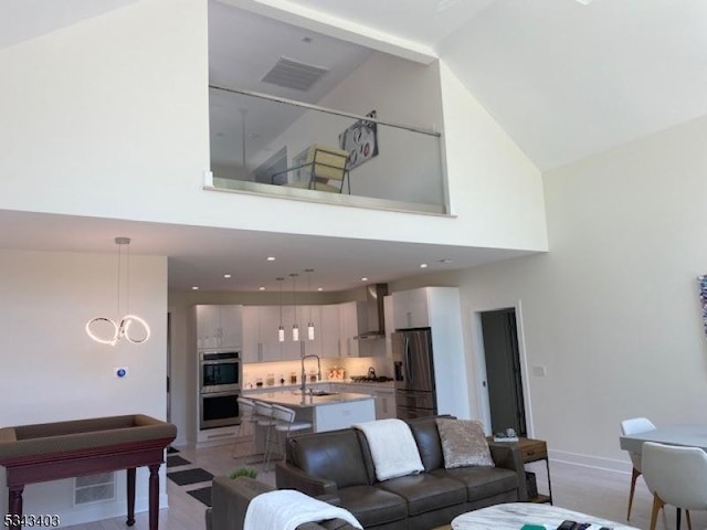 living area featuring a notable chandelier, visible vents, high vaulted ceiling, and baseboards