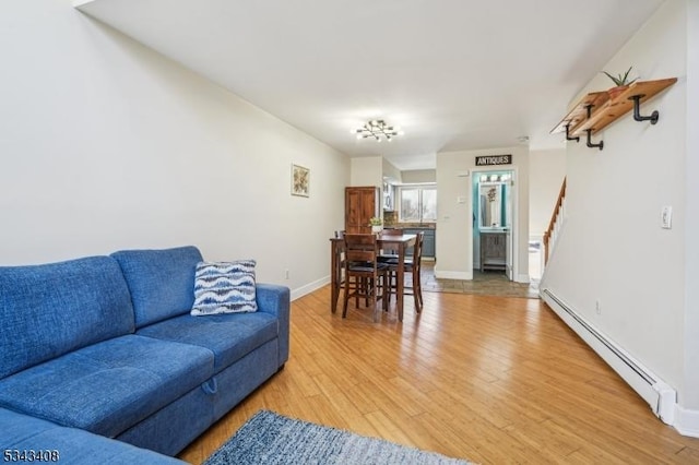 living room featuring stairway, light wood-style floors, baseboards, and baseboard heating