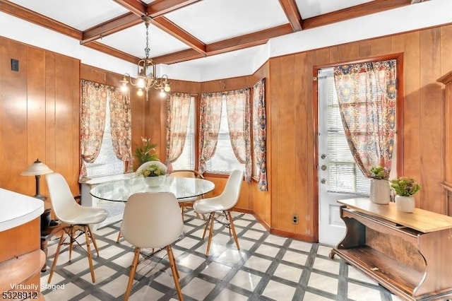 dining area featuring a notable chandelier, wood walls, coffered ceiling, and beamed ceiling