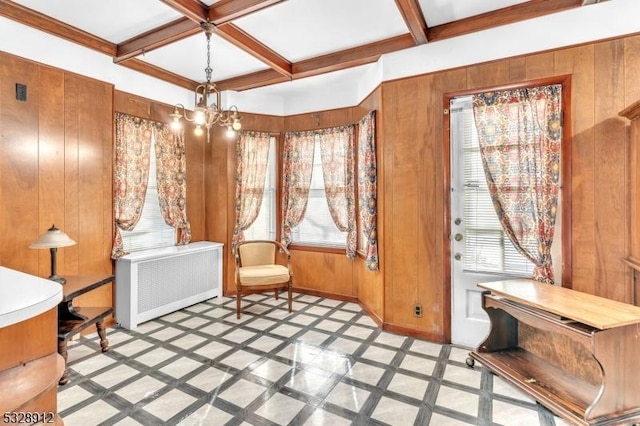 living area featuring coffered ceiling, radiator, a healthy amount of sunlight, and wood walls