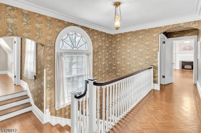 hall with wallpapered walls, crown molding, baseboards, and arched walkways