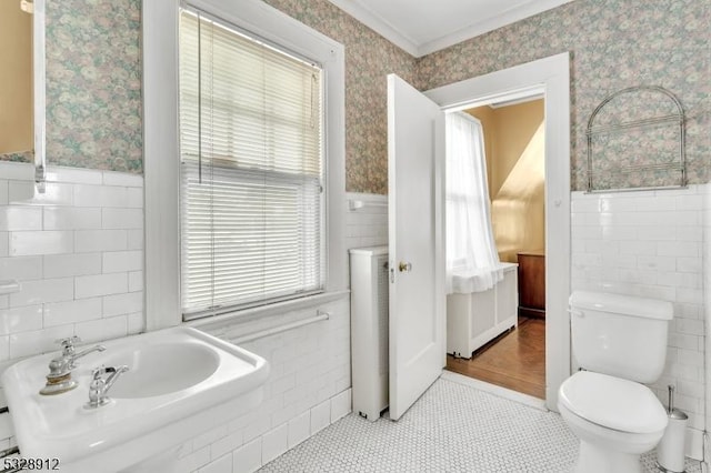 bathroom featuring a wainscoted wall, toilet, wallpapered walls, and tile walls