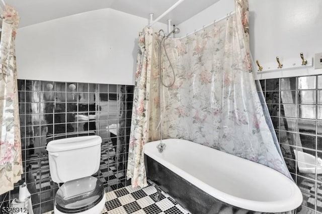 full bathroom featuring tile patterned flooring, toilet, tile walls, and vaulted ceiling