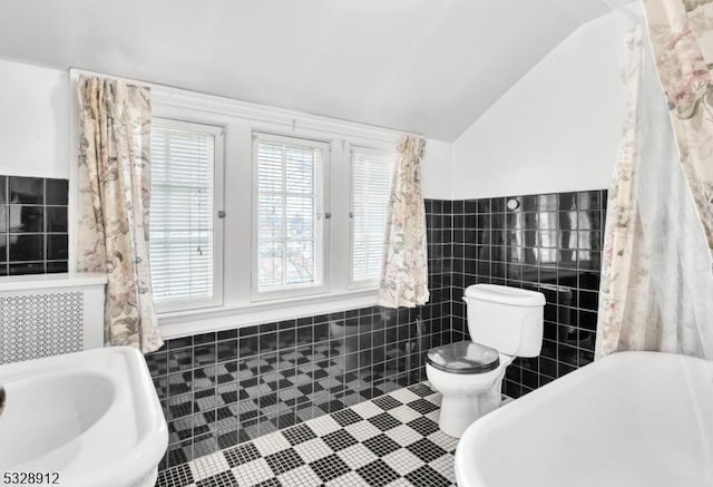 full bath featuring a sink, vaulted ceiling, tile walls, toilet, and tile patterned floors