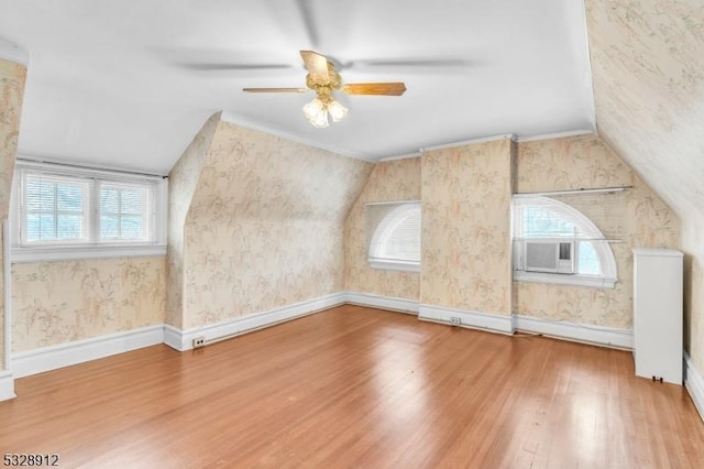 additional living space featuring vaulted ceiling, wallpapered walls, baseboards, and wood finished floors