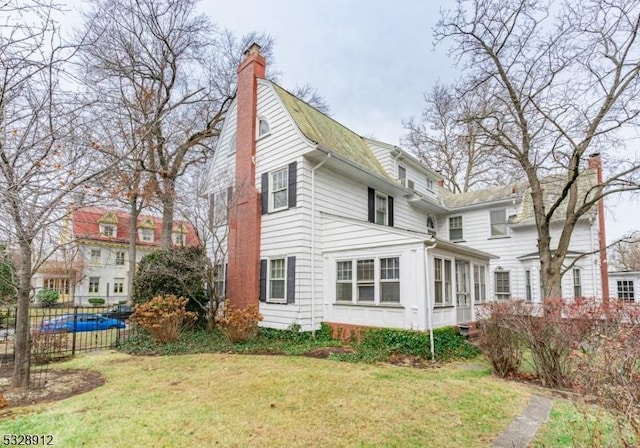 rear view of property with fence, a lawn, and a chimney