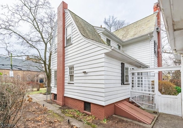 view of side of property featuring a shingled roof and a chimney