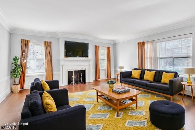 living area featuring wood finished floors, plenty of natural light, a fireplace, and ornamental molding