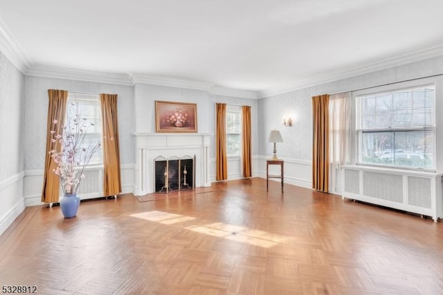 unfurnished living room with crown molding, a wainscoted wall, radiator heating unit, a fireplace, and a decorative wall