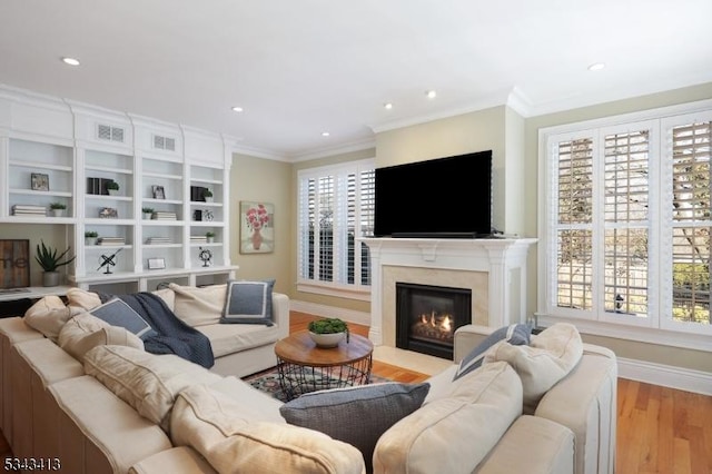 living area with ornamental molding, wood finished floors, a high end fireplace, recessed lighting, and baseboards