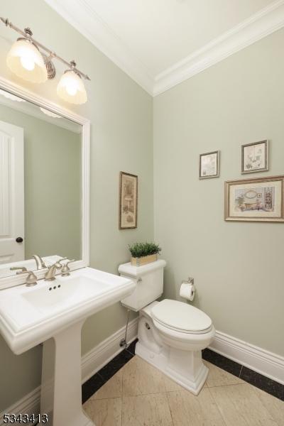 bathroom featuring tile patterned flooring, toilet, crown molding, and baseboards