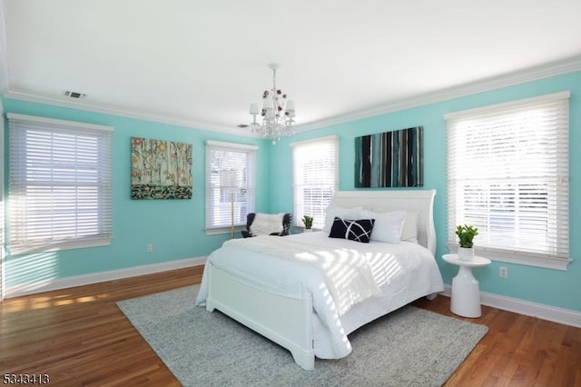 bedroom with wood finished floors, baseboards, an inviting chandelier, and ornamental molding