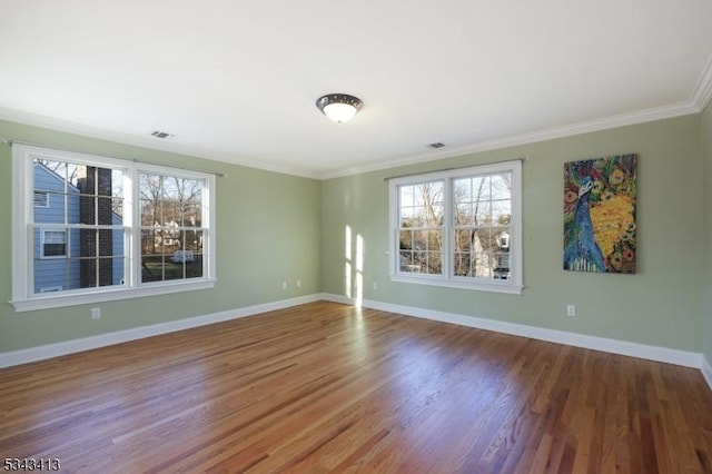 unfurnished room with a wealth of natural light, visible vents, baseboards, and wood finished floors