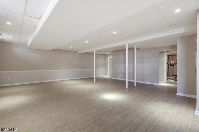 finished basement with recessed lighting, wood finished floors, baseboards, and a drop ceiling