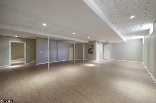 finished basement featuring stairway, wood finished floors, baseboards, recessed lighting, and a paneled ceiling