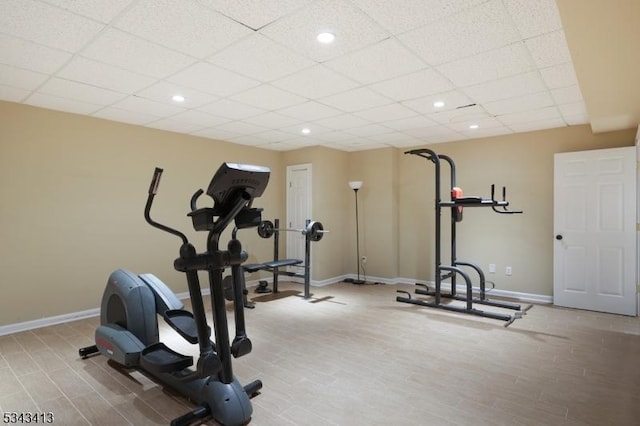 workout area with a drop ceiling, recessed lighting, baseboards, and wood finished floors