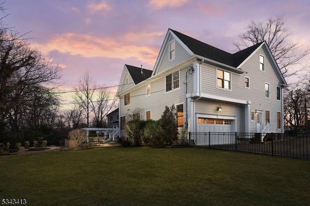 property exterior at dusk featuring a lawn, a garage, and fence