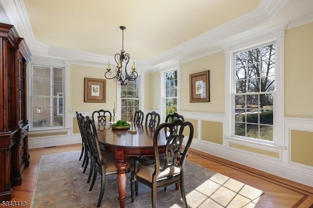 dining area featuring crown molding, a notable chandelier, and wood finished floors