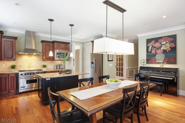 dining room with recessed lighting, crown molding, and light wood finished floors