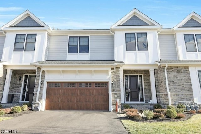 view of front of home with stone siding, driveway, and an attached garage