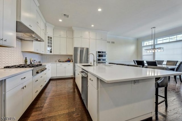 kitchen featuring visible vents, a sink, a kitchen breakfast bar, backsplash, and appliances with stainless steel finishes