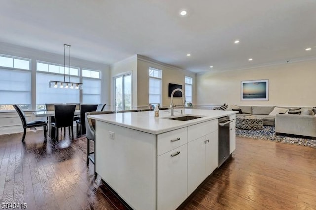 kitchen featuring dark wood finished floors, open floor plan, an island with sink, ornamental molding, and a sink