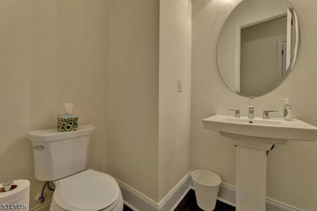 half bath featuring toilet and baseboards