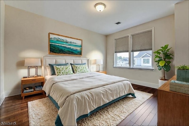 bedroom with visible vents, baseboards, and wood finished floors