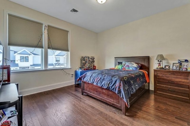 bedroom with wood finished floors, visible vents, and baseboards