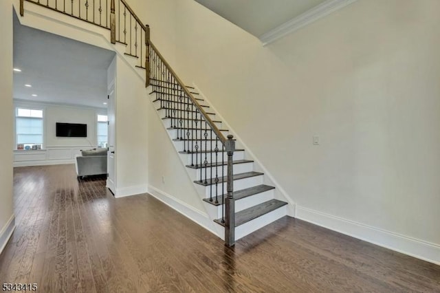 stairs featuring baseboards, ornamental molding, recessed lighting, a high ceiling, and wood finished floors