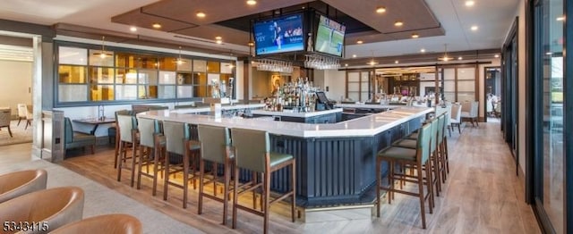 bar with a community bar, wood finished floors, and recessed lighting