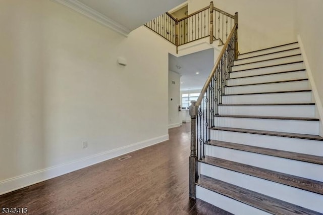 staircase featuring visible vents, baseboards, wood finished floors, and crown molding