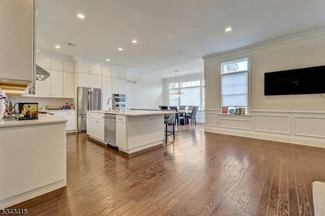 kitchen with stainless steel appliances, ornamental molding, dark wood-style flooring, and light countertops