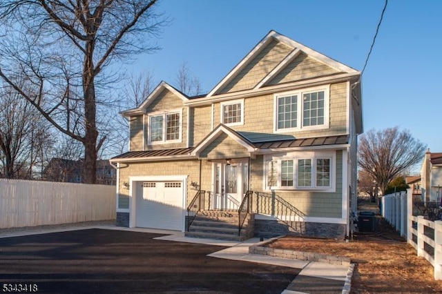 craftsman house featuring driveway, a standing seam roof, fence, an attached garage, and metal roof