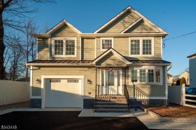 craftsman-style house with driveway, a standing seam roof, fence, metal roof, and a garage